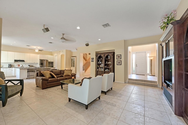 living area featuring light tile patterned floors, ceiling fan, recessed lighting, and stairway