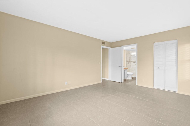 629 Sea Pine Way Unit D1, Greenacres, FL 33415 - unfurnished bedroom with baseboards, connected bathroom, tile patterned flooring, and a closet