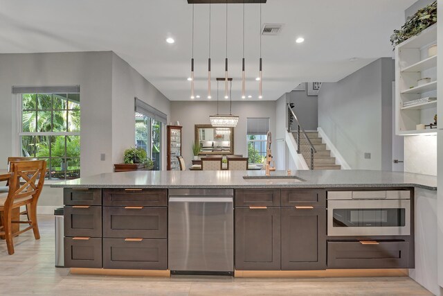 127 Via Castilla, Jupiter, FL 33458 - kitchen featuring stainless steel dishwasher, a sink, oven, light stone countertops, and dark brown cabinets