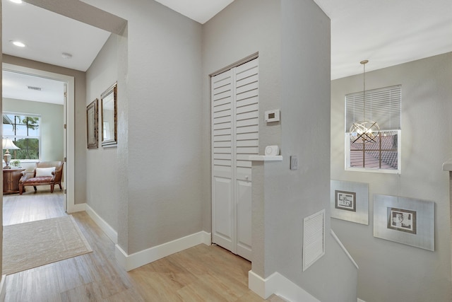 127 Via Castilla, Jupiter, FL 33458 - hallway with light wood-type flooring, baseboards, and a chandelier
