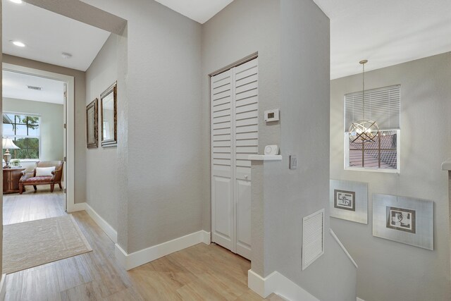 127 Via Castilla, Jupiter, FL 33458 - hallway featuring light wood-style floors and a chandelier