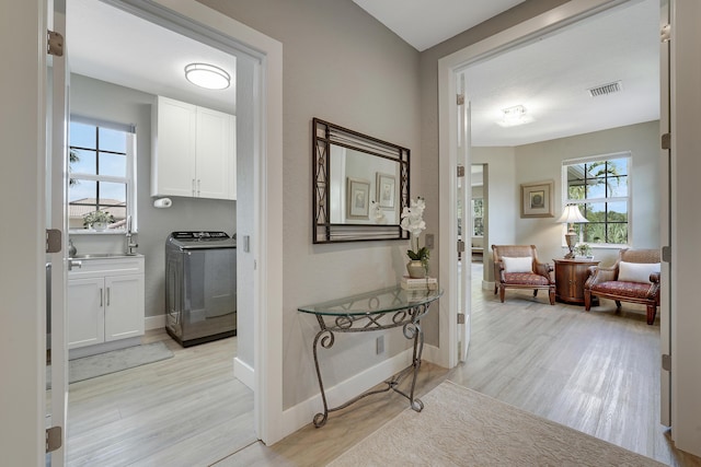 127 Via Castilla, Jupiter, FL 33458 - hallway with washer / dryer, light wood finished floors, and baseboards