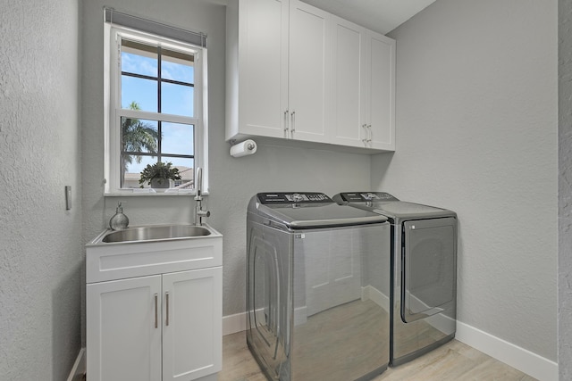 127 Via Castilla, Jupiter, FL 33458 - laundry area with washing machine and clothes dryer, cabinet space, light wood-type flooring, a textured wall, and baseboards