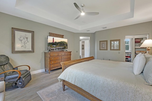 127 Via Castilla, Jupiter, FL 33458 - bedroom with a tray ceiling, light wood-style flooring, baseboards, and a ceiling fan