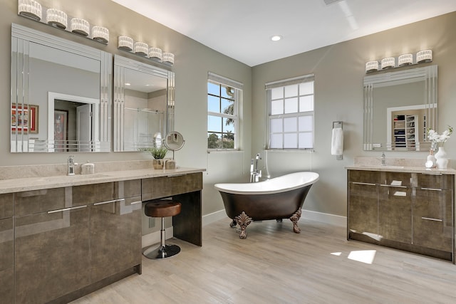 127 Via Castilla, Jupiter, FL 33458 - bathroom with two vanities, wood finished floors, baseboards, a freestanding tub, and a shower stall