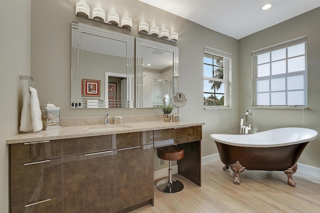 127 Via Castilla, Jupiter, FL 33458 - full bath featuring wood finished floors, a freestanding bath, vanity, baseboards, and recessed lighting