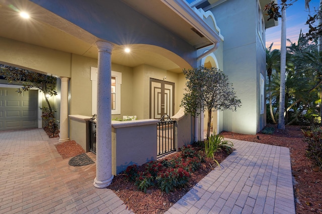 127 Via Castilla, Jupiter, FL 33458 - exterior entry at dusk featuring stucco siding, a garage, and a gate