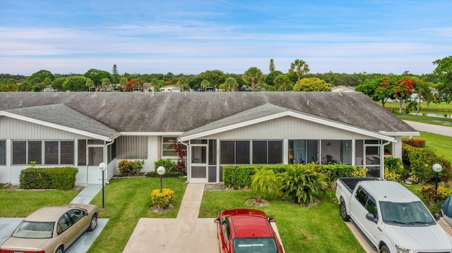 3477 Christopher St Unit 3477, West Palm Beach, FL 33417 - back of house featuring a sunroom, a shingled roof, and a lawn