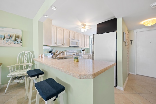 kitchen with white appliances, light countertops, light tile patterned floors, a peninsula, and a sink