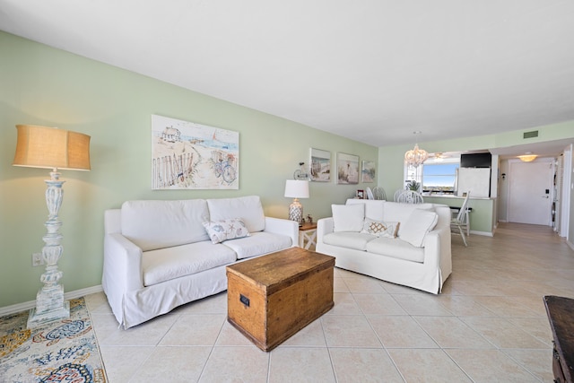 living room with a chandelier, light tile patterned floors, and baseboards