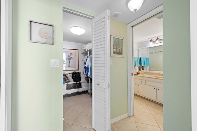 hall with light tile patterned floors and a sink