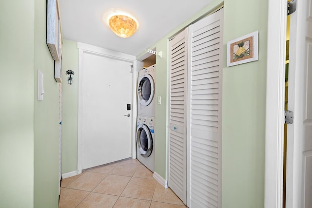 laundry room with stacked washer / dryer, light tile patterned floors, and baseboards