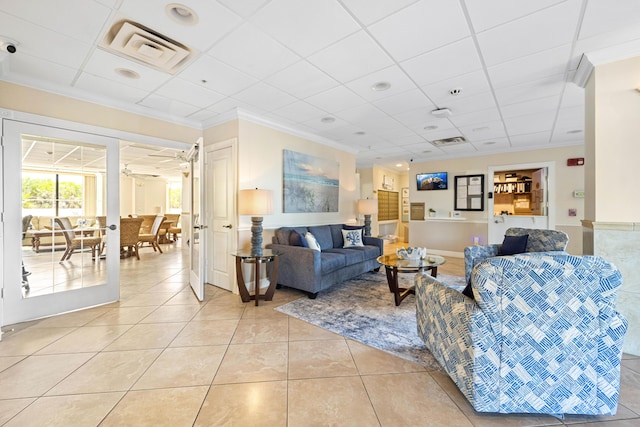 living area with light tile patterned flooring, ornamental molding, and a drop ceiling