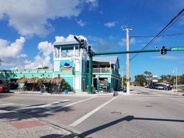 view of asphalt street featuring traffic lights, curbs, sidewalks, traffic signs, and street lights