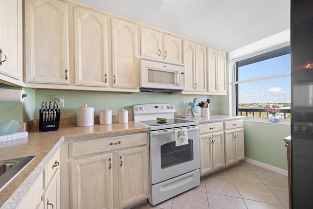 kitchen with white appliances, light tile patterned floors, light countertops, baseboards, and a sink