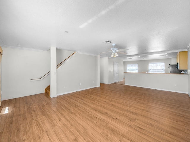 1898 SE Interlachen Dr, Port Saint Lucie, FL 34952 - unfurnished living room featuring a ceiling fan, a textured ceiling, crown molding, stairway, and light wood-type flooring