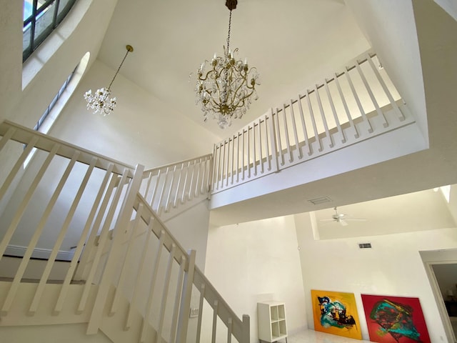 staircase featuring a high ceiling, a chandelier, and ceiling fan