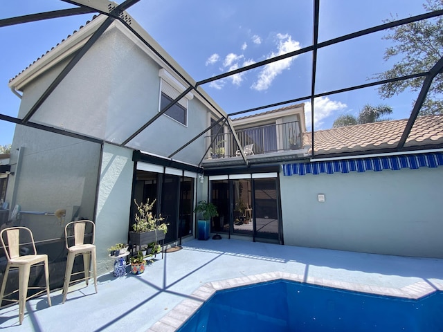 10039 Lexington Cir N, Boynton Beach, FL 33436 - rear view of property with a balcony, a patio, stucco siding, a lanai, and an outdoor pool