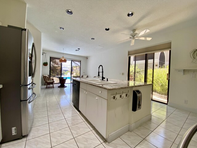 kitchen with a sink, stainless steel fridge with ice dispenser, black dishwasher, an island with sink, and a textured ceiling