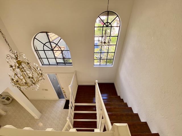 staircase with a chandelier, baseboards, and a towering ceiling