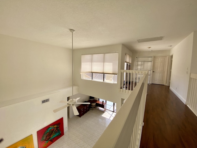 hallway with an upstairs landing and a textured ceiling
