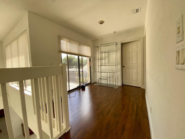 empty room with dark wood-style flooring and a textured wall