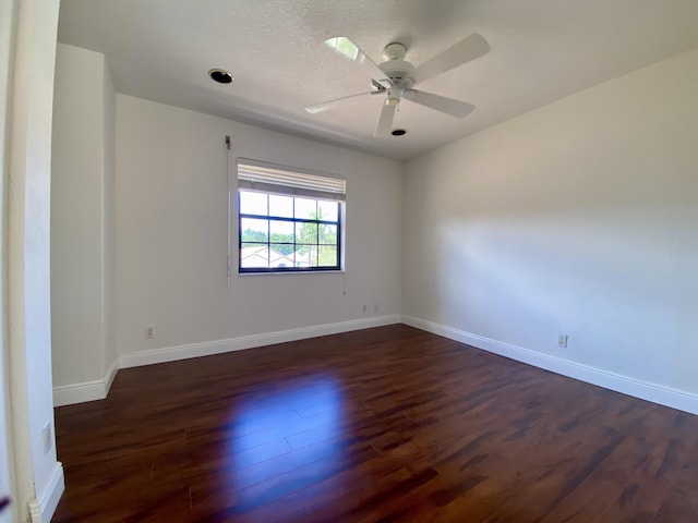 unfurnished room with dark wood-type flooring, ceiling fan, and baseboards
