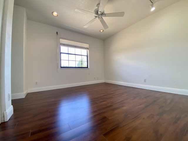 empty room with dark wood finished floors, ceiling fan, and baseboards