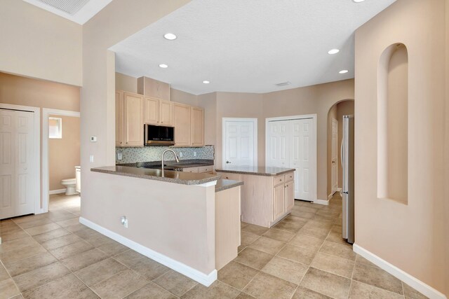 3588 Turtle Island Ct, West Palm Beach, FL 33411 - kitchen with stainless steel appliances, light brown cabinets, arched walkways, backsplash, and recessed lighting