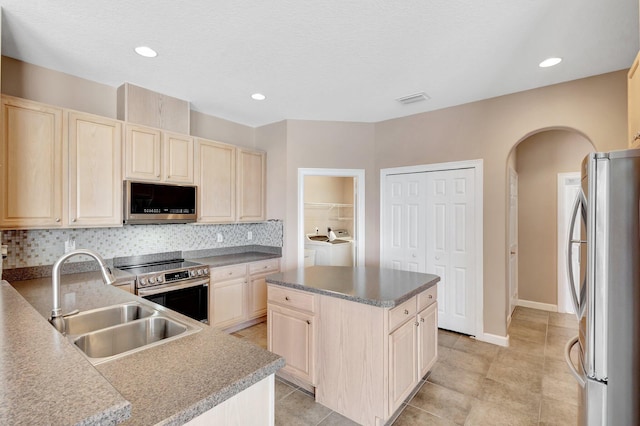 3588 Turtle Island Ct, West Palm Beach, FL 33411 - kitchen with appliances with stainless steel finishes, a sink, washer and dryer, light brown cabinetry, and arched walkways