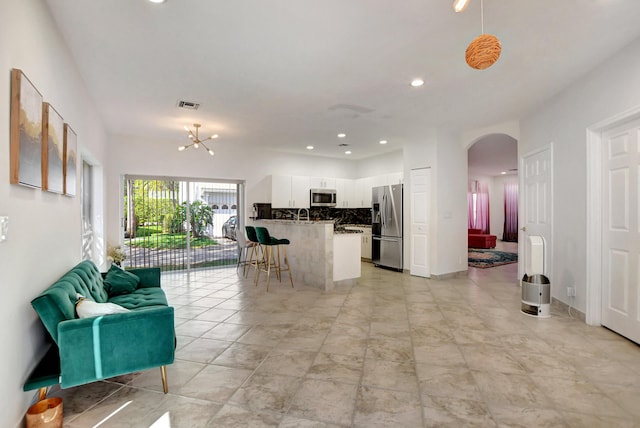 kitchen featuring appliances with stainless steel finishes, arched walkways, open floor plan, white cabinets, and backsplash