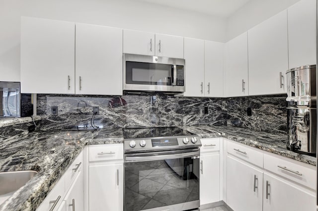kitchen featuring stainless steel appliances, dark stone counters, white cabinets, and decorative backsplash
