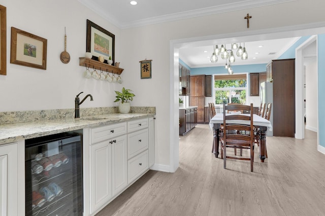 765 Lagoon Dr, North Palm Beach, FL 33408 - indoor wet bar featuring beverage cooler, crown molding, light wood-style flooring, baseboards, and a chandelier