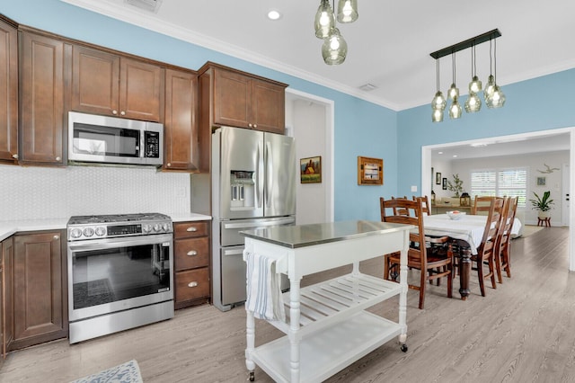 765 Lagoon Dr, North Palm Beach, FL 33408 - kitchen featuring stainless steel appliances, light wood-style flooring, crown molding, decorative light fixtures, and decorative backsplash