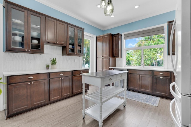 765 Lagoon Dr, North Palm Beach, FL 33408 - kitchen with freestanding refrigerator, light wood-style flooring, light countertops, dark brown cabinets, and tasteful backsplash