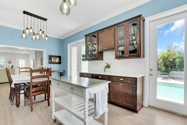 765 Lagoon Dr, North Palm Beach, FL 33408 - kitchen featuring light wood finished floors, light countertops, decorative light fixtures, glass insert cabinets, and ornamental molding
