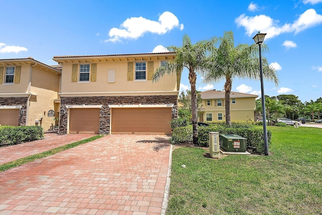 view of front of home featuring stucco siding, decorative driveway, a garage, a front lawn, and stone siding