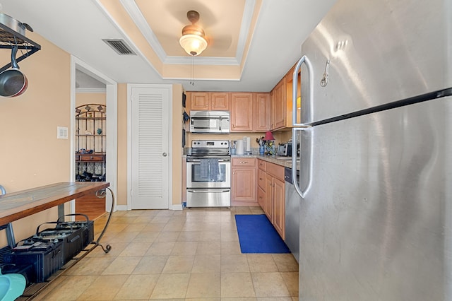kitchen with stainless steel appliances, a tray ceiling, ornamental molding, light tile patterned floors, and light countertops