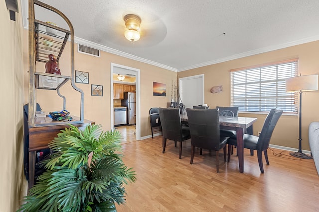 dining area featuring light wood-style floors, ornamental molding, a textured ceiling, and baseboards