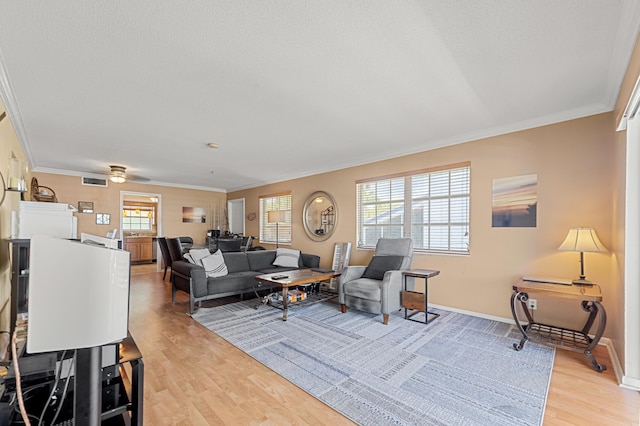 living area featuring crown molding, light wood finished floors, and baseboards