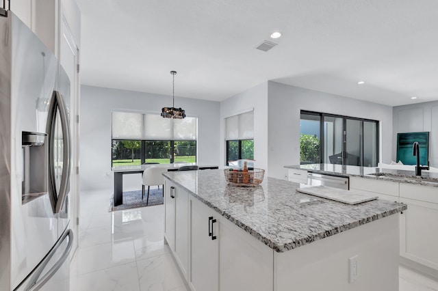 kitchen featuring stainless steel appliances, a kitchen island, a sink, a chandelier, and white cabinetry