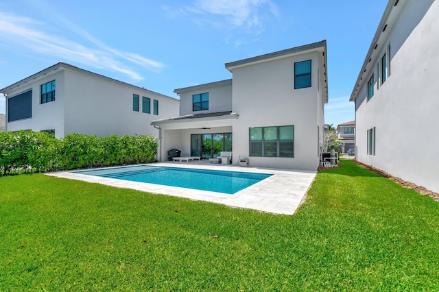 back of property featuring stucco siding, a patio, a yard, and an outdoor pool