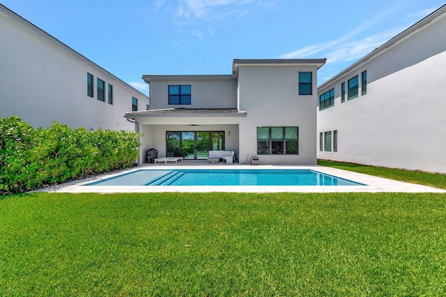 back of property featuring stucco siding, an outdoor pool, a lawn, and a patio
