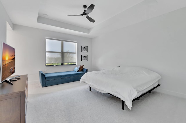carpeted bedroom featuring a raised ceiling, a ceiling fan, and baseboards