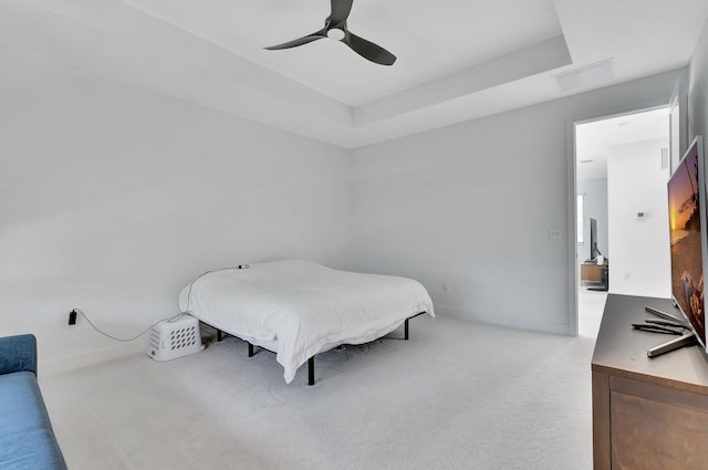 bedroom featuring light colored carpet, ceiling fan, and a tray ceiling