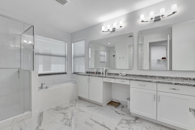bathroom featuring a stall shower, a garden tub, vanity, and marble finish floors