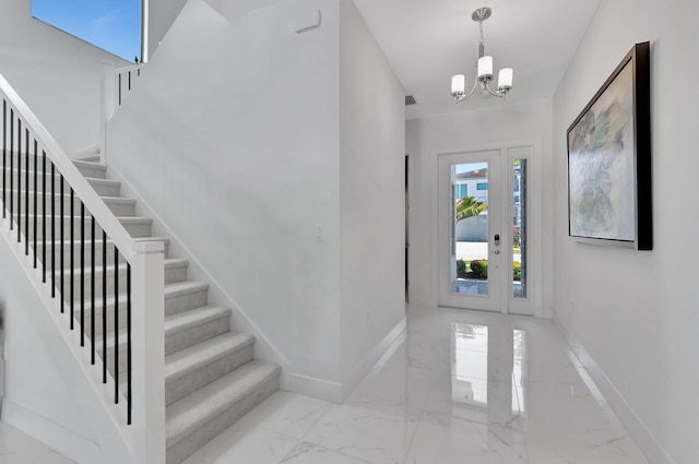 entrance foyer with stairs, marble tiled floors, baseboards, and a chandelier