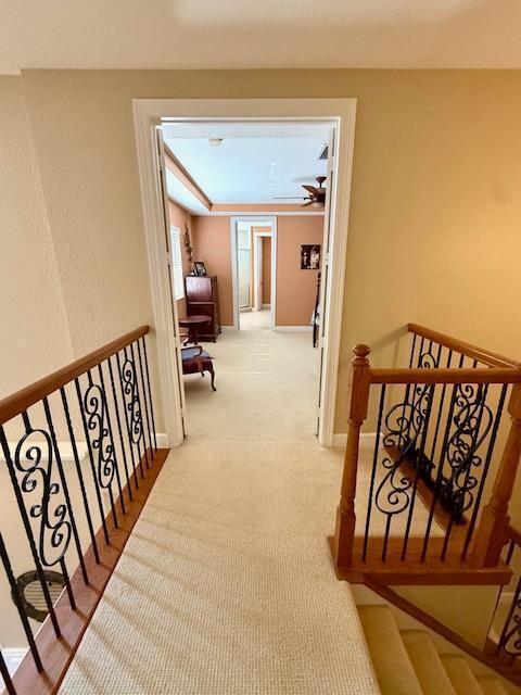 corridor featuring an upstairs landing and carpet