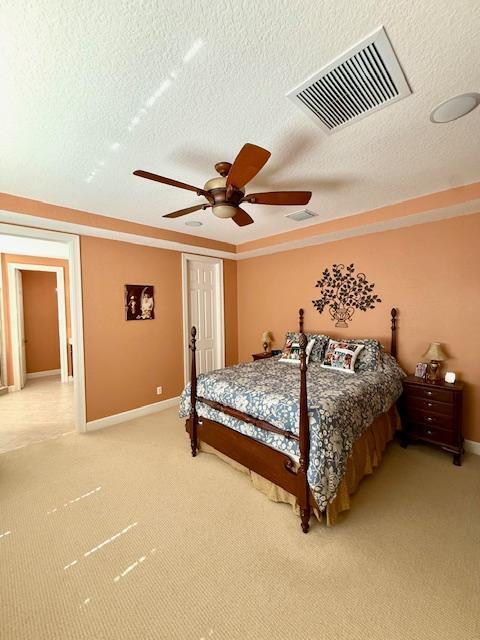bedroom featuring a textured ceiling, light carpet, baseboards, and a ceiling fan