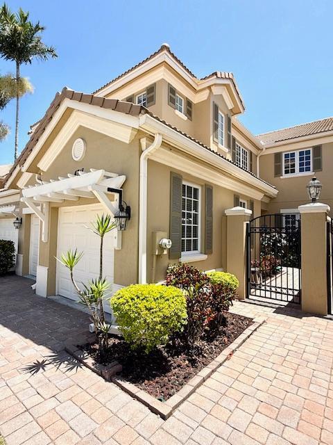 view of front of house with stucco siding, an attached garage, a gate, fence, and driveway